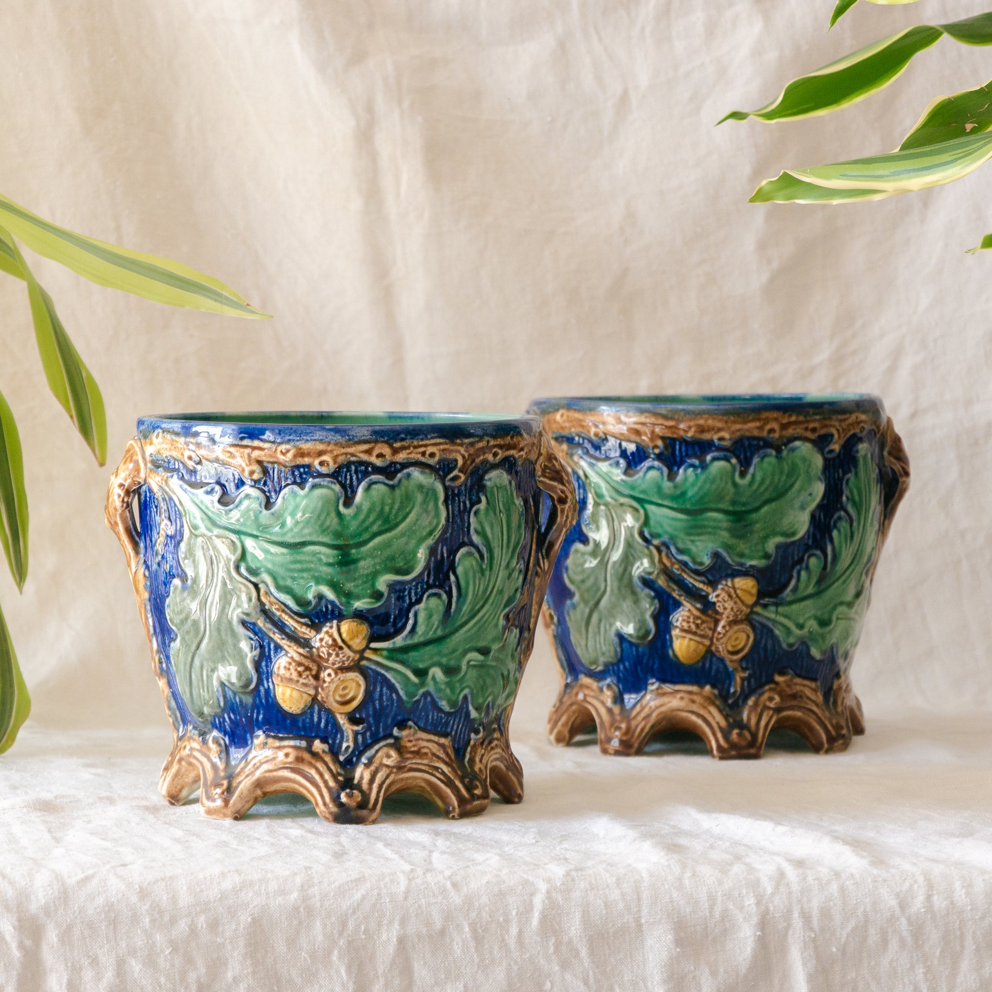 A stunning pair of French antique majolica planters, absolutely glorious fresh blue and green colours with oak leafs and acorns in relief making these stunning pieces of interior home decor wherever you decide to display them.

One of the planters has an antique repair in the form of metal staples that have been expertly done from the inside - in the 1800s and early 1900s this was quite a common repair to have made on items of high value and we feel it only adds to the authenticity/story of these pieces.