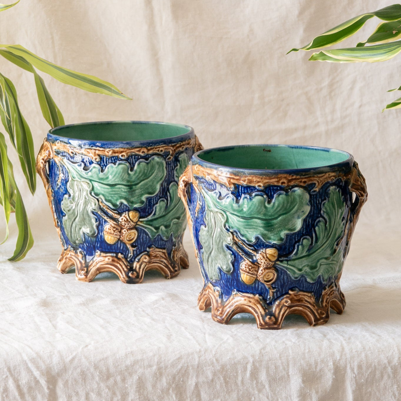 A stunning pair of French antique majolica planters, absolutely glorious fresh blue and green colours with oak leafs and acorns in relief making these stunning pieces of interior home decor wherever you decide to display them.

One of the planters has an antique repair in the form of metal staples that have been expertly done from the inside - in the 1800s and early 1900s this was quite a common repair to have made on items of high value and we feel it only adds to the authenticity/story of these pieces.
