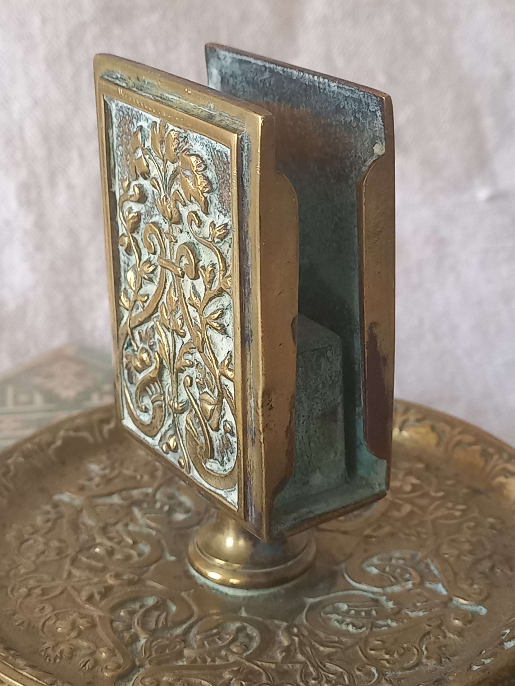 Close-up of a French antique decorative brass-coated matchbox holder in a decorative setting.