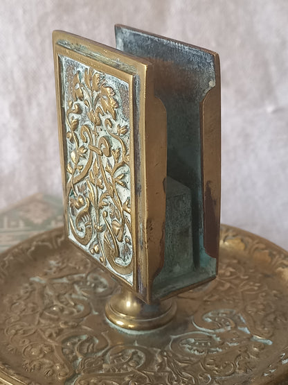 Close-up of a French antique decorative brass-coated matchbox holder in a decorative setting.