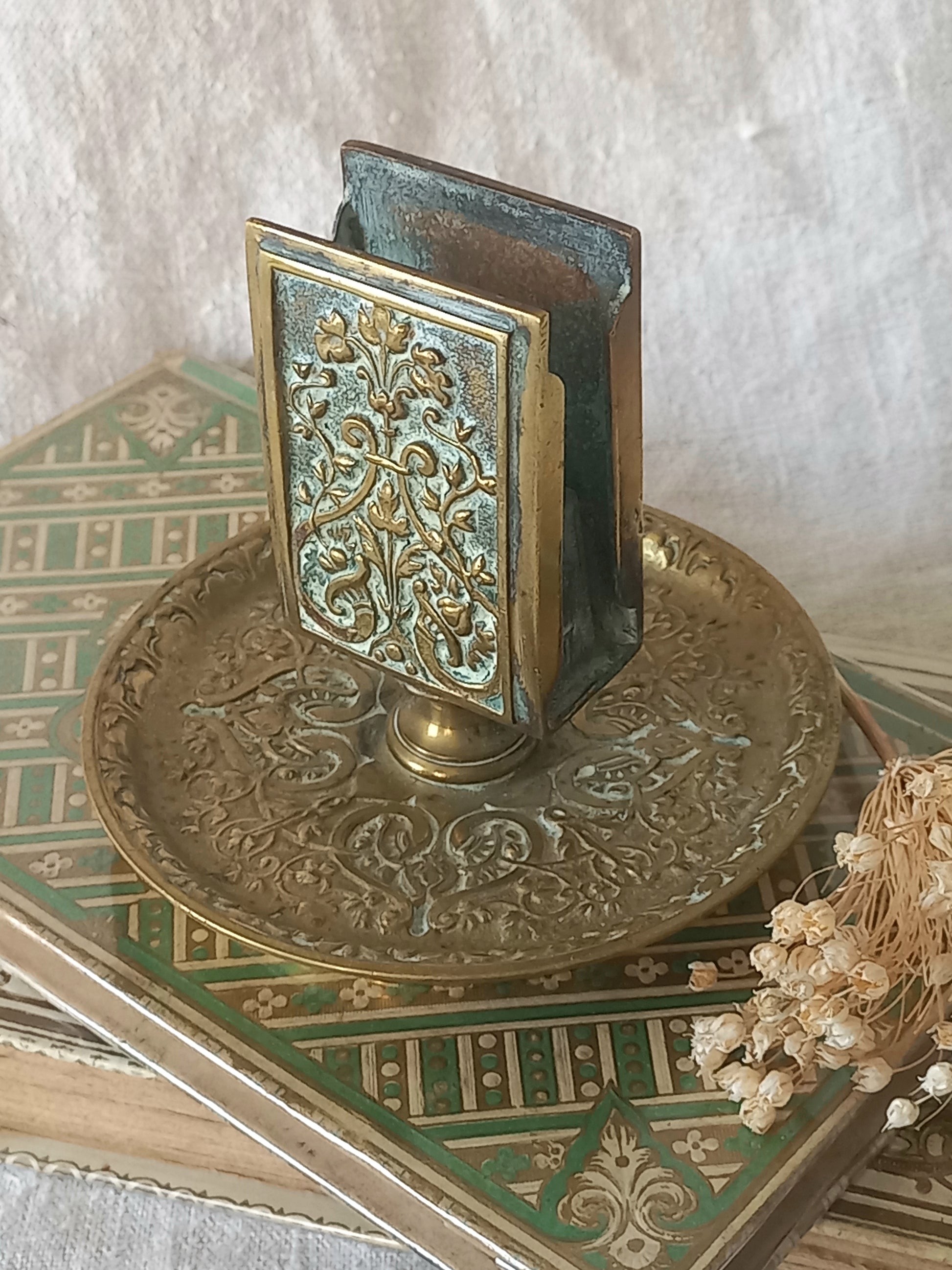 Close-up of a French antique decorative brass-coated matchbox holder in a decorative setting.