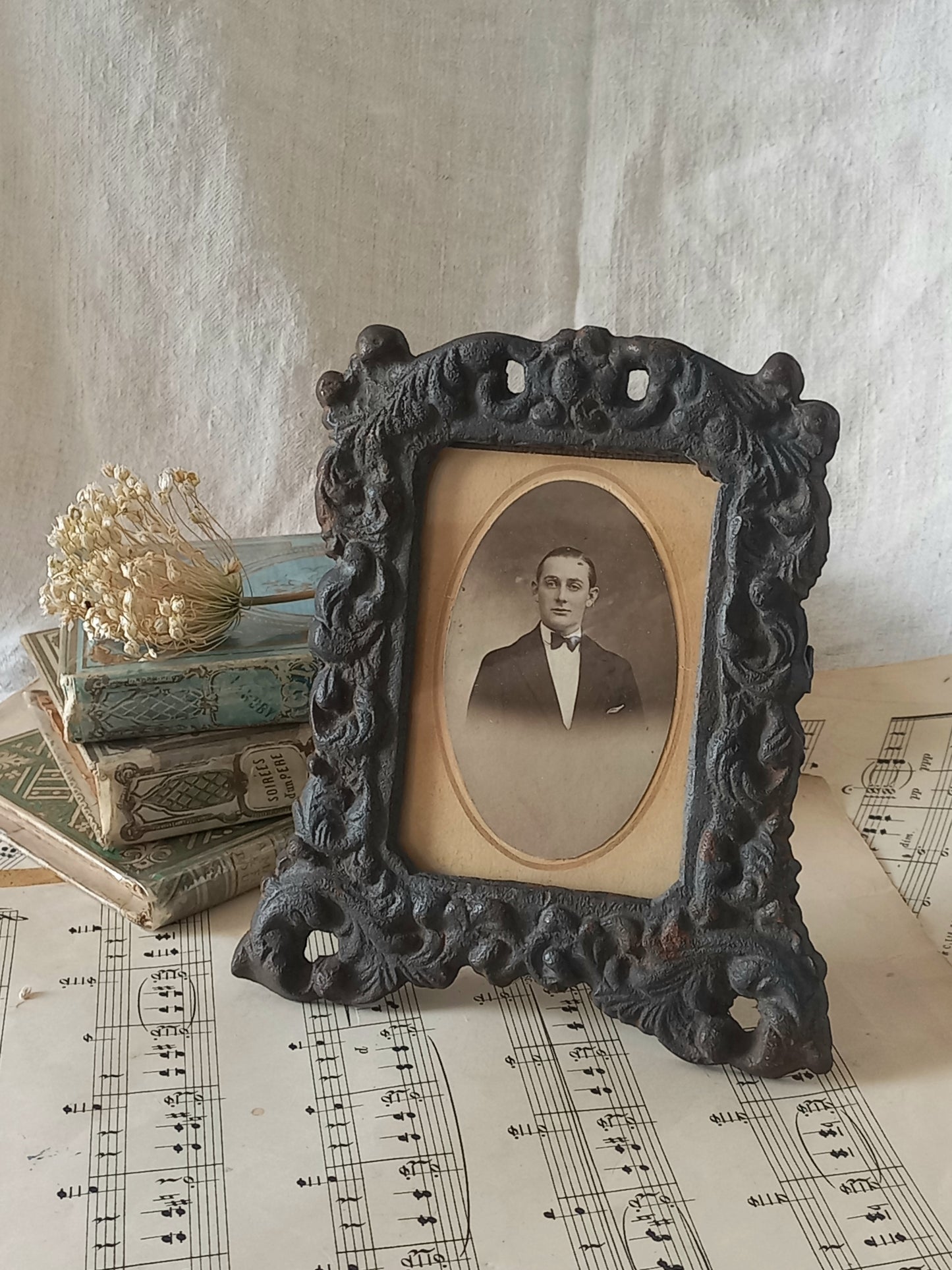 A small French antique decorative cast iron photo frame with time-worn patina. There is a glass front and a hardboard backing board. Inside is an original period photo.