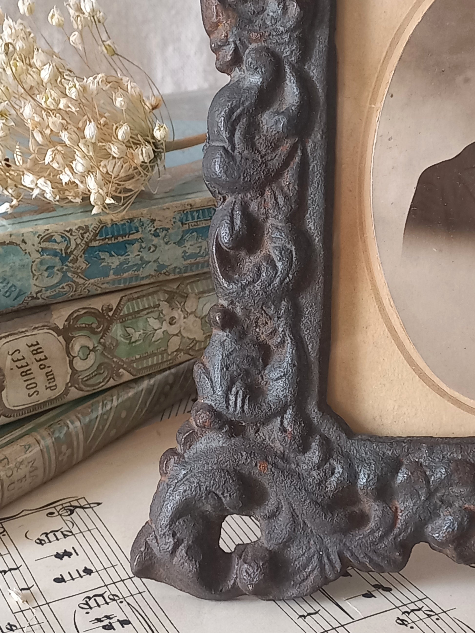 A small French antique decorative cast iron photo frame with time-worn patina. There is a glass front and a hardboard backing board. Inside is an original period photo.