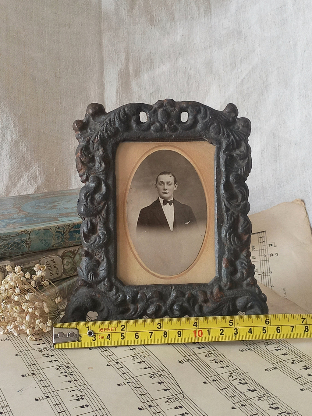 A small French antique decorative cast iron photo frame with time-worn patina. There is a glass front and a hardboard backing board. Inside is an original period photo.