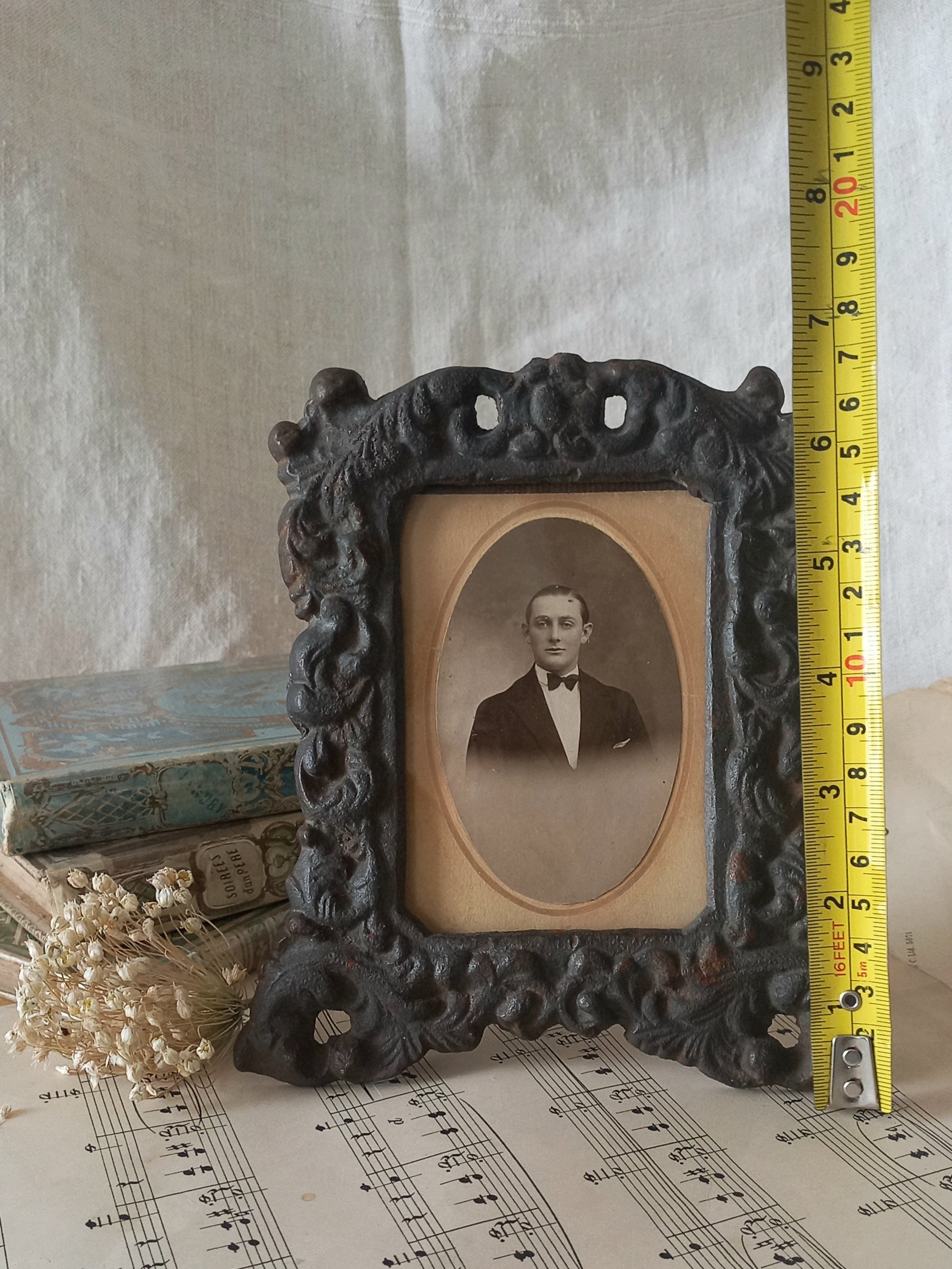 A small French antique decorative cast iron photo frame with time-worn patina. There is a glass front and a hardboard backing board. Inside is an original period photo.