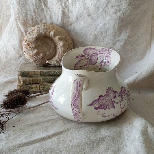White ceramic vase with purple floral patterns on a textured fabric background