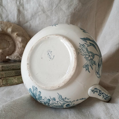 Ceramic pot with teal floral patterns on a textured surface