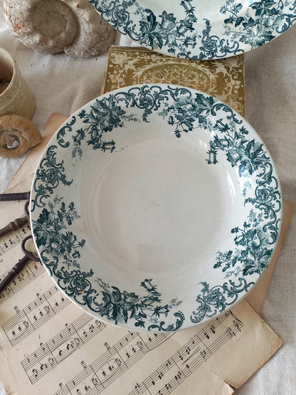 Decorative ceramic plate with green floral pattern on a surface with music sheet and shells.