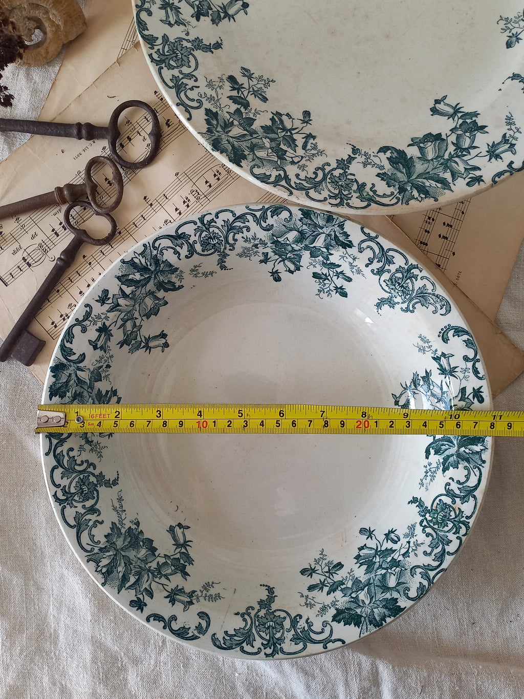 Two ceramic plates with floral patterns and a measuring tape between them on a textured surface.