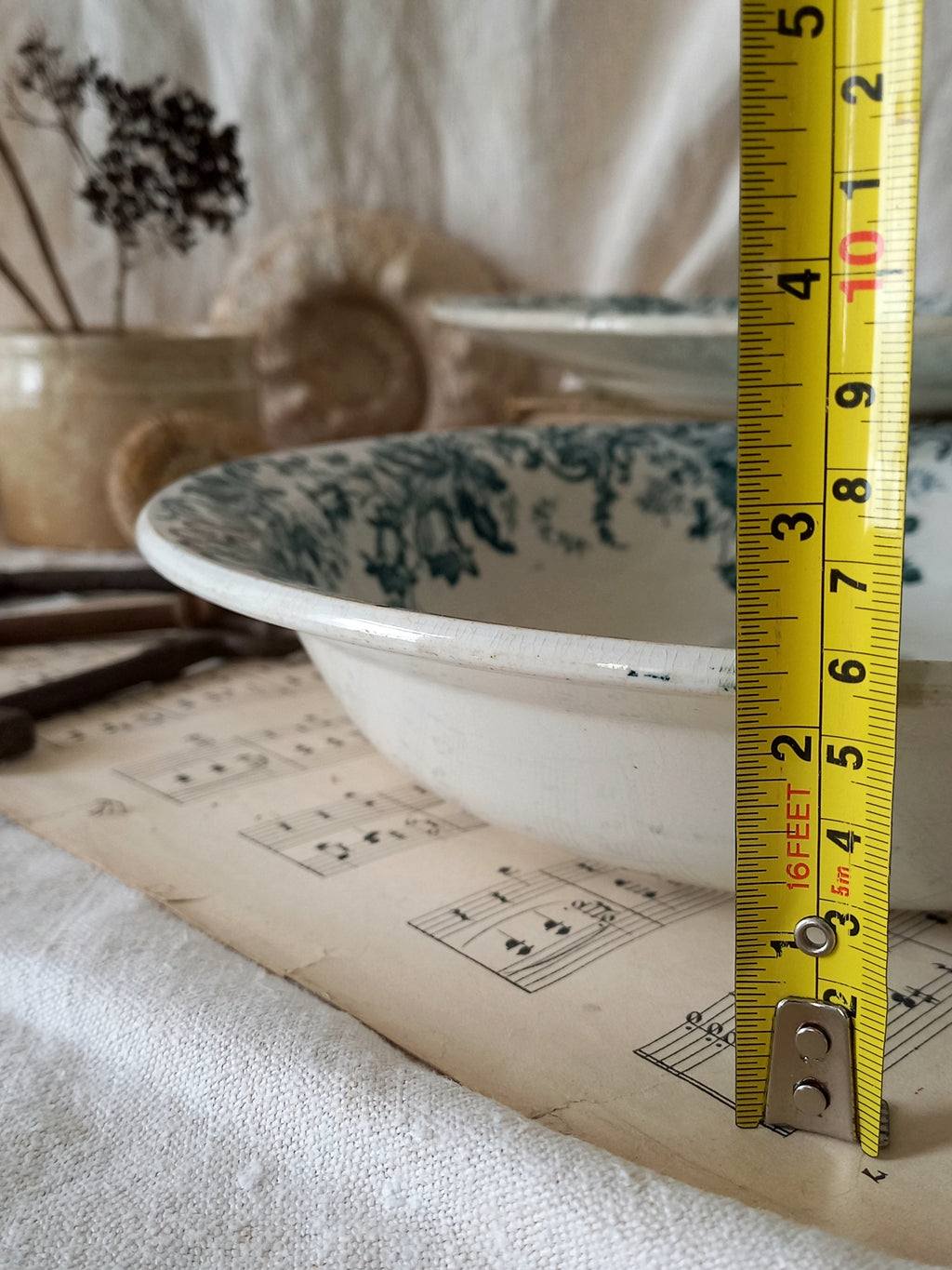 Measuring tape next to a vintage ceramic bowl on a surface with a blurred background