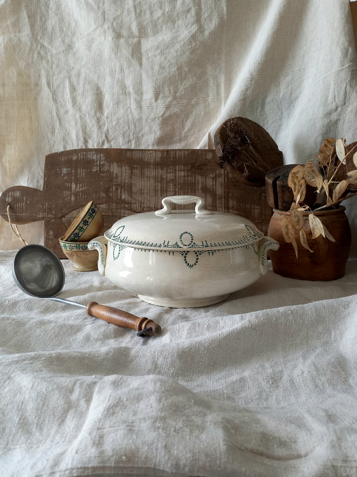 White ceramic covered dish with decorative patterns on a white fabric background