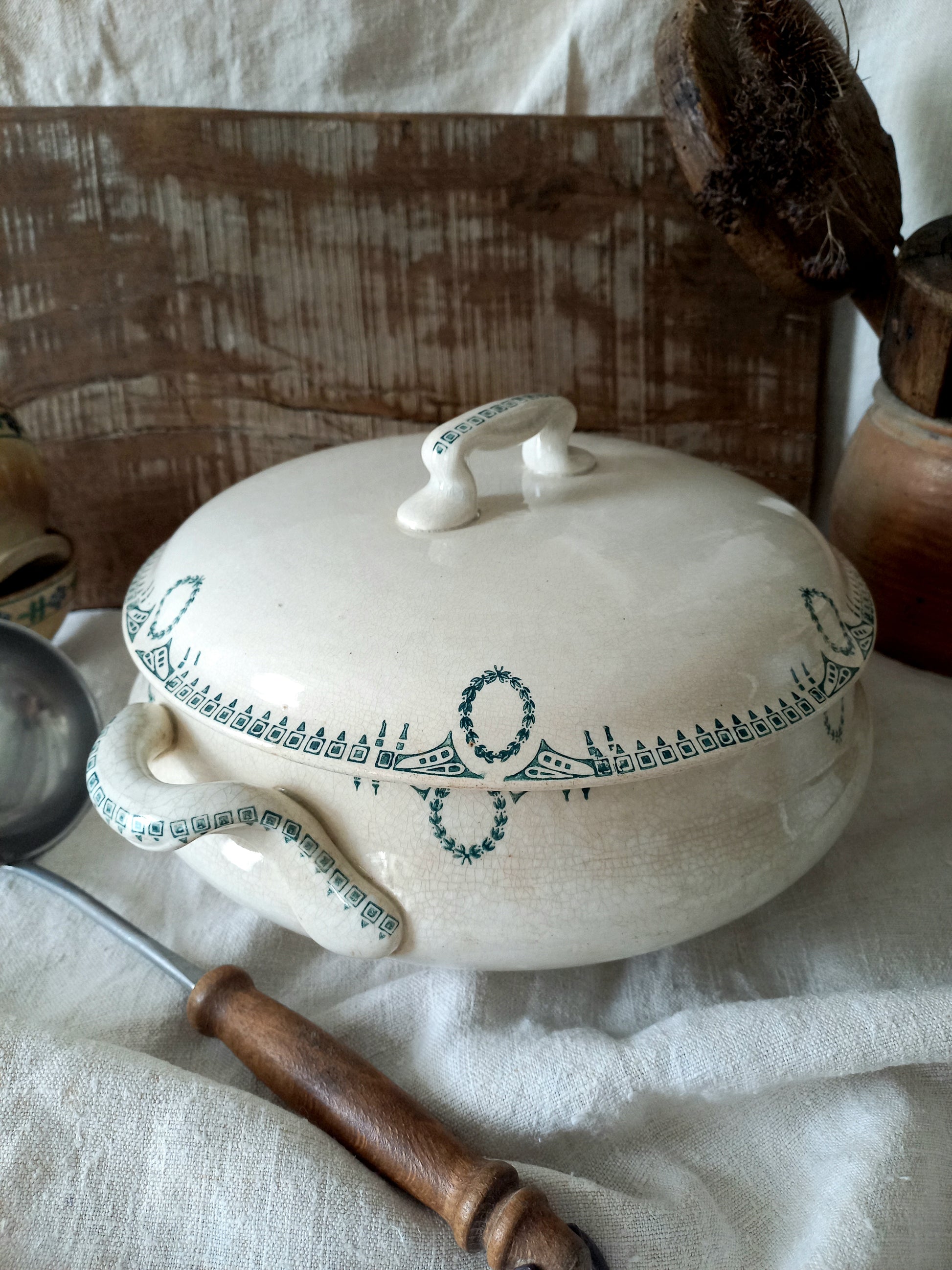 White ceramic tureen with green patterns on a white cloth background
