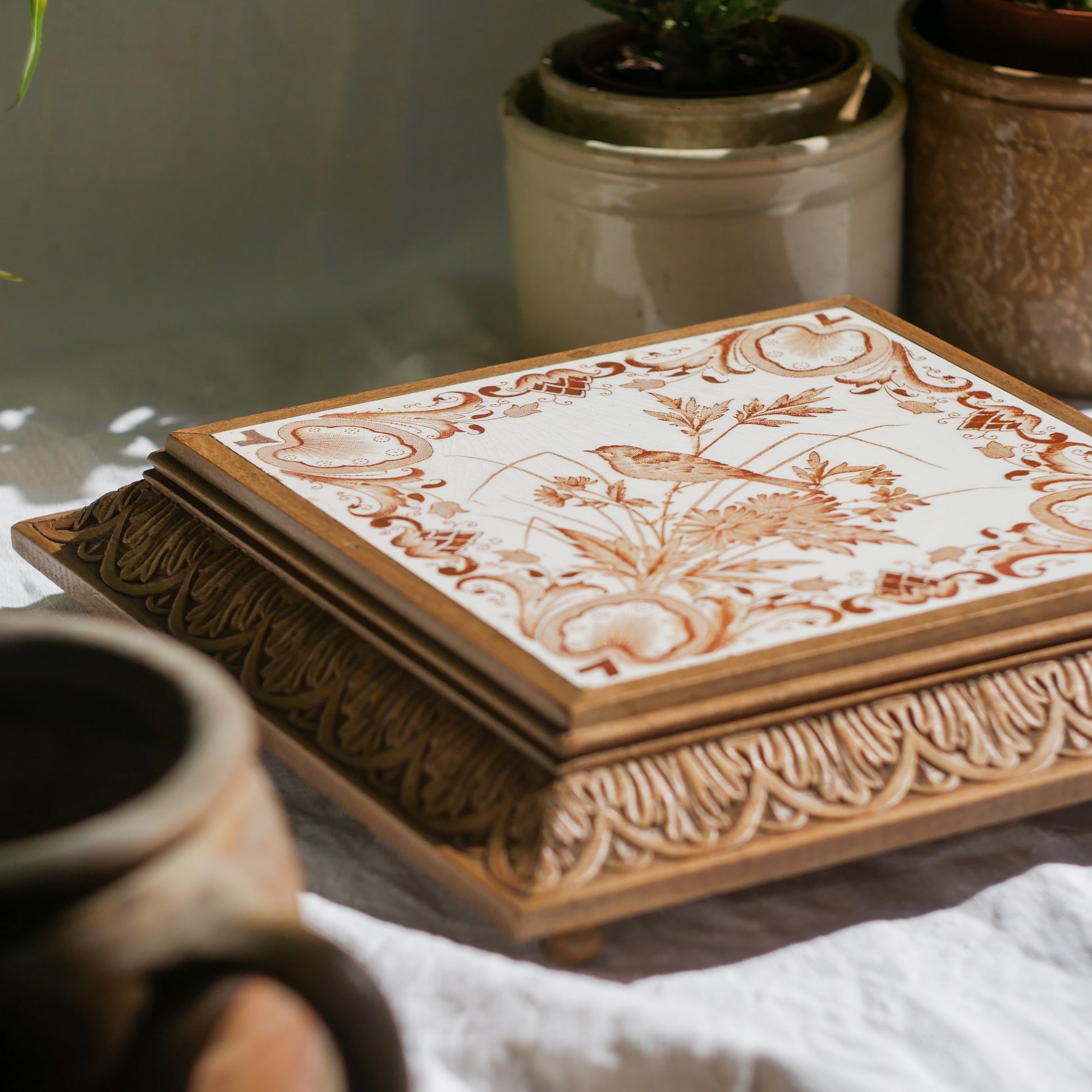 A beautiful French antique wooden trivet with a ceramic bird and floral tile insert. The wooden frame is very decorative with patterns around all four edges while the ceramic tile has aged just enough, the tasteful off-white and light brown colour scheme making this piece a most welcome addition to any kitchen as decor or perhaps as a decorative plant pot stand.