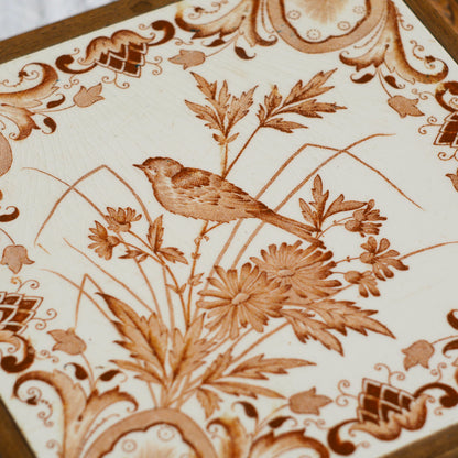 A beautiful French antique wooden trivet with a ceramic bird and floral tile insert. The wooden frame is very decorative with patterns around all four edges while the ceramic tile has aged just enough, the tasteful off-white and light brown colour scheme making this piece a most welcome addition to any kitchen as decor or perhaps as a decorative plant pot stand.