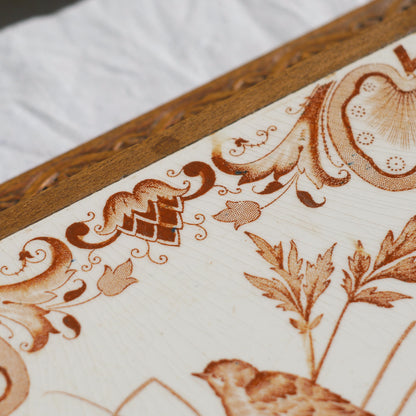 A beautiful French antique wooden trivet with a ceramic bird and floral tile insert. The wooden frame is very decorative with patterns around all four edges while the ceramic tile has aged just enough, the tasteful off-white and light brown colour scheme making this piece a most welcome addition to any kitchen as decor or perhaps as a decorative plant pot stand.