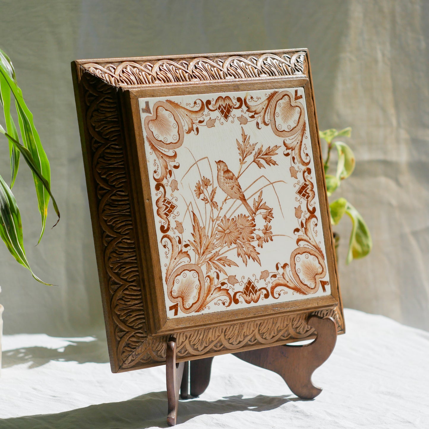 A beautiful French antique wooden trivet with a ceramic bird and floral tile insert. The wooden frame is very decorative with patterns around all four edges while the ceramic tile has aged just enough, the tasteful off-white and light brown colour scheme making this piece a most welcome addition to any kitchen as decor or perhaps as a decorative plant pot stand.