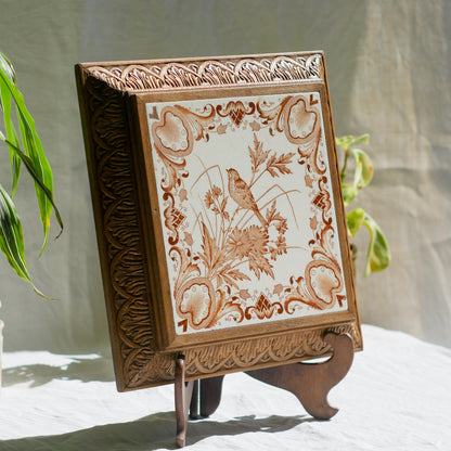 A beautiful French antique wooden trivet with a ceramic bird and floral tile insert. The wooden frame is very decorative with patterns around all four edges while the ceramic tile has aged just enough, the tasteful off-white and light brown colour scheme making this piece a most welcome addition to any kitchen as decor or perhaps as a decorative plant pot stand.