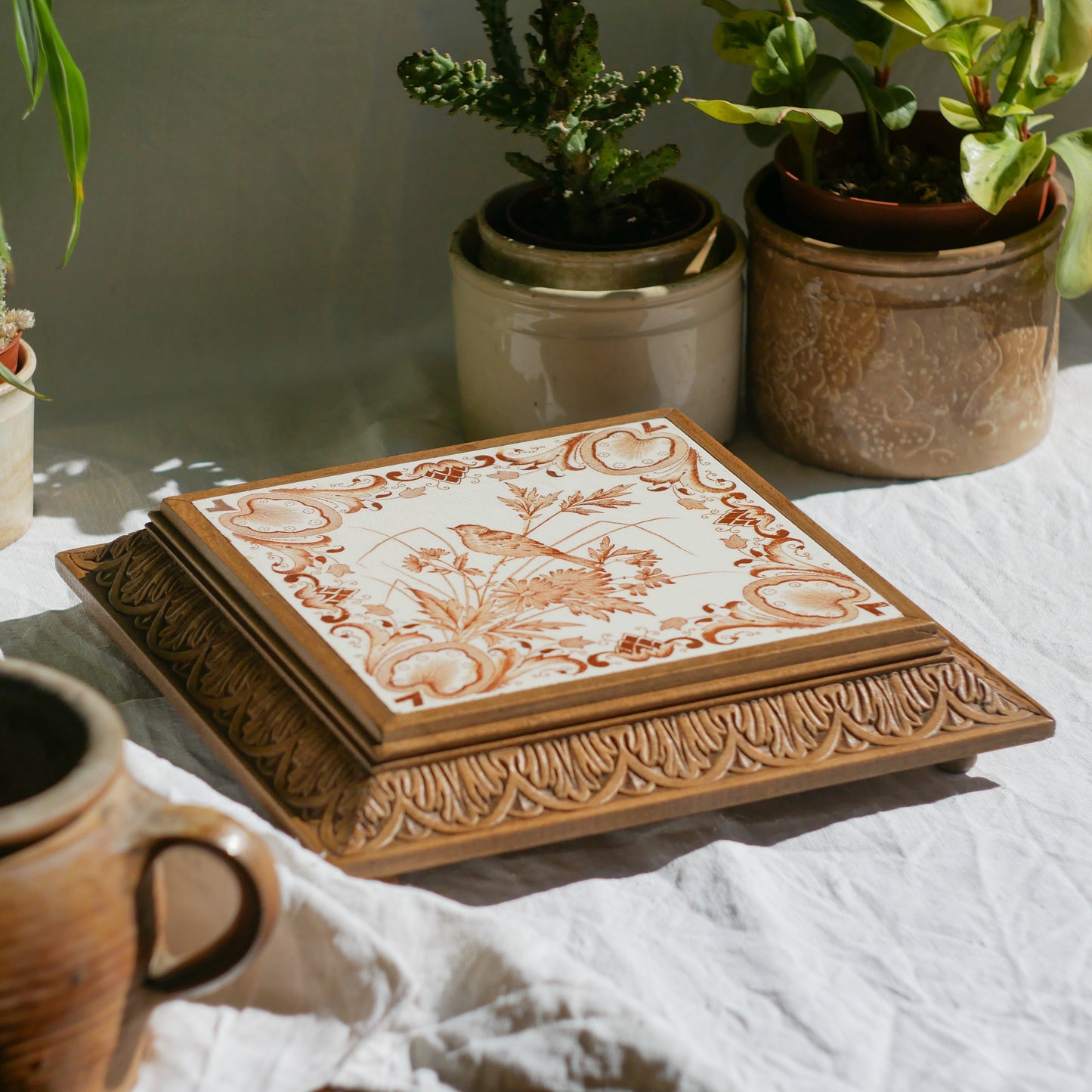 A beautiful French antique wooden trivet with a ceramic bird and floral tile insert. The wooden frame is very decorative with patterns around all four edges while the ceramic tile has aged just enough, the tasteful off-white and light brown colour scheme making this piece a most welcome addition to any kitchen as decor or perhaps as a decorative plant pot stand.