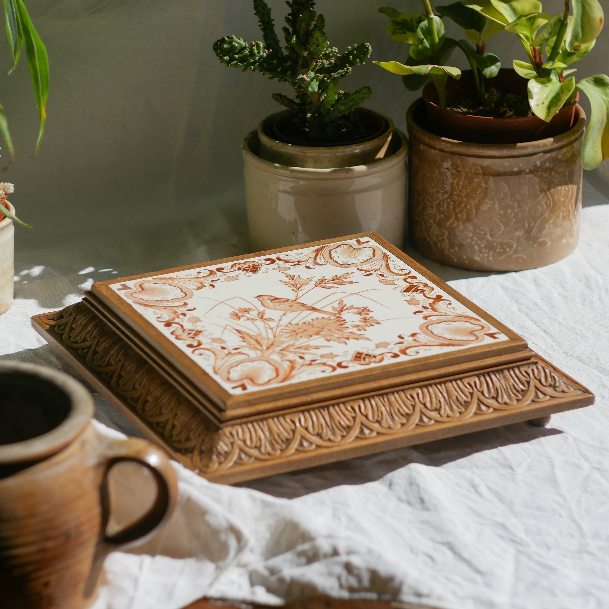 A beautiful French antique wooden trivet with a ceramic bird and floral tile insert. The wooden frame is very decorative with patterns around all four edges while the ceramic tile has aged just enough, the tasteful off-white and light brown colour scheme making this piece a most welcome addition to any kitchen as decor or perhaps as a decorative plant pot stand.
