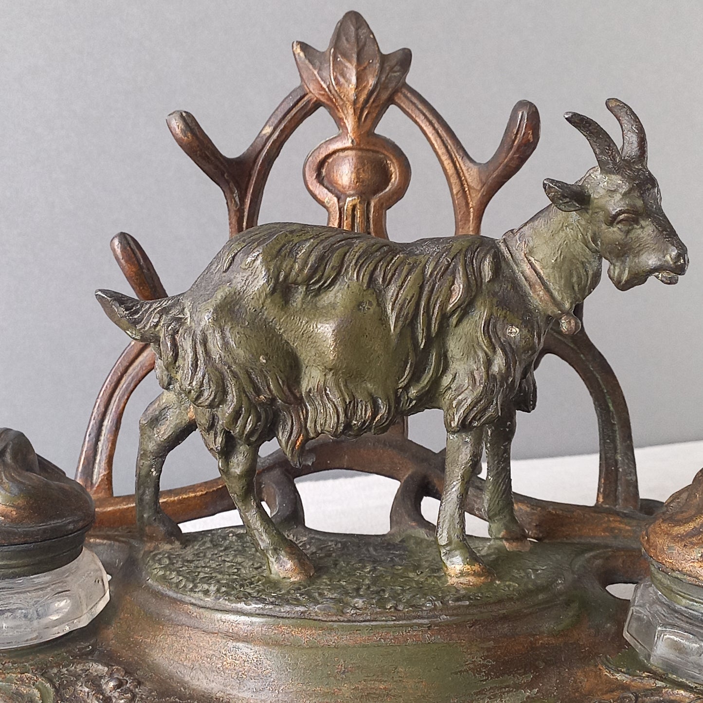 A stunning French art nouveau double inkwell with a goat figurine.

This wonderful antique inkwell has been sculpted in metal and signed by the artist (see photos). Behind the beautiful goat figurine are two pen rests and either side of the goat are two small glass ink pots with decorative metal lids.

The metal is finished in a lovely shade of green that has worn over time with traces of gold colour beneath - it has a wonderful patina of time all over it.