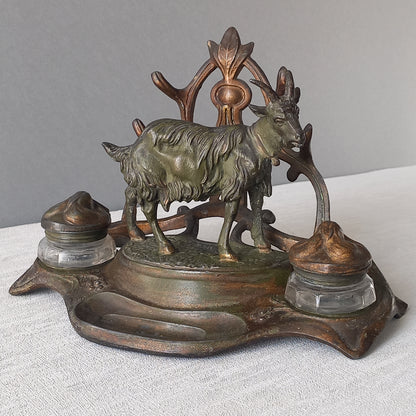 A stunning French art nouveau double inkwell with a goat figurine.

This wonderful antique inkwell has been sculpted in metal and signed by the artist (see photos). Behind the beautiful goat figurine are two pen rests and either side of the goat are two small glass ink pots with decorative metal lids.

The metal is finished in a lovely shade of green that has worn over time with traces of gold colour beneath - it has a wonderful patina of time all over it.