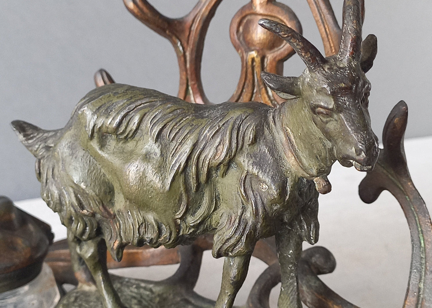 A stunning French art nouveau double inkwell with a goat figurine.

This wonderful antique inkwell has been sculpted in metal and signed by the artist (see photos). Behind the beautiful goat figurine are two pen rests and either side of the goat are two small glass ink pots with decorative metal lids.

The metal is finished in a lovely shade of green that has worn over time with traces of gold colour beneath - it has a wonderful patina of time all over it.
