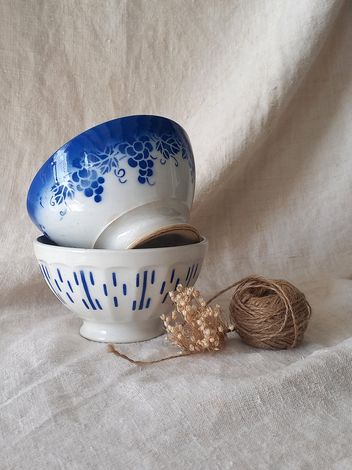Two ceramic bowls with blue patterns on a textured surface with twine.