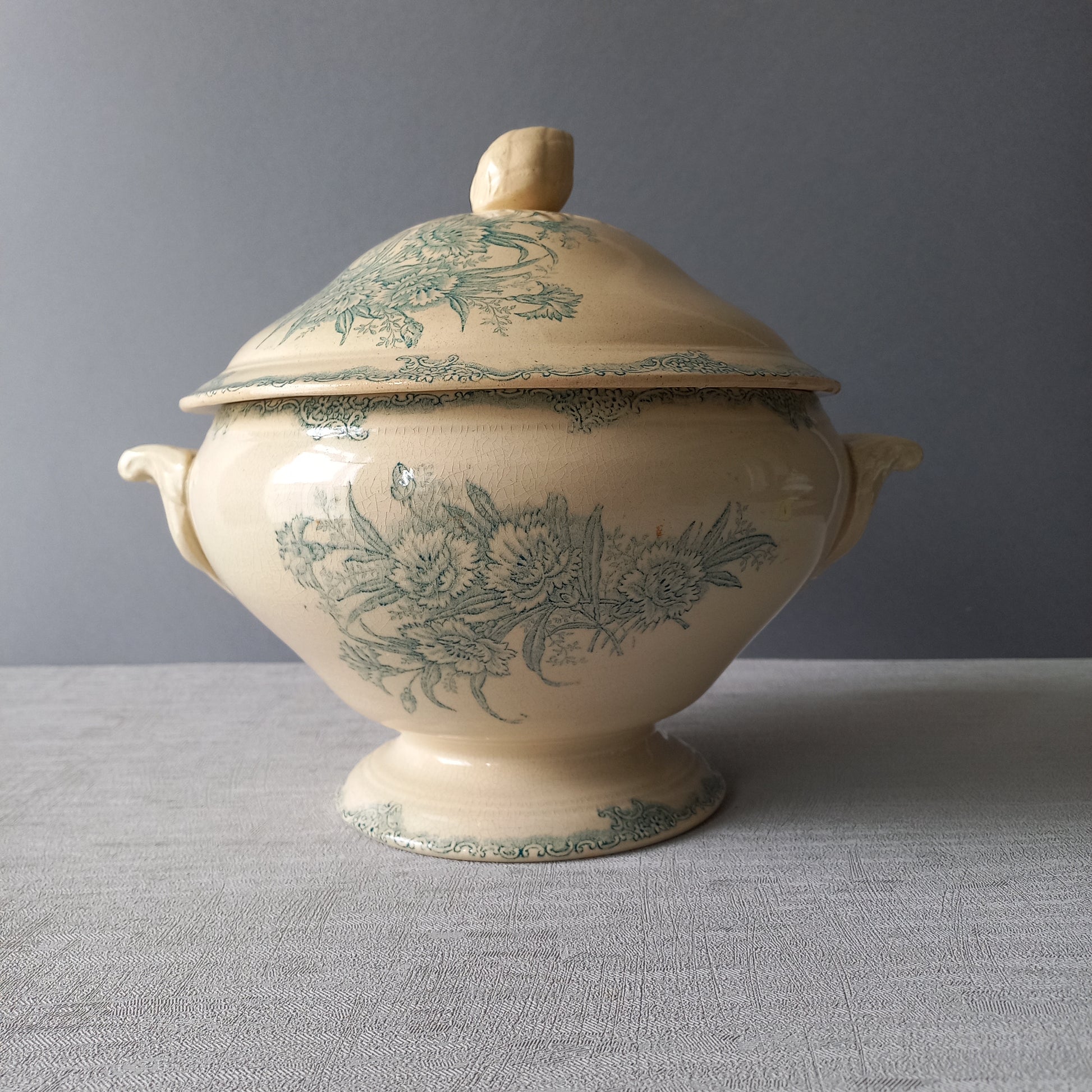 A pretty antique ironstone soup tureen with aged and faded floral transfer pattern in a beautiful shade of blue green or teal. Over time this wonderful old tureen has developed a pleasing faded creamy white finish. In summary, a beautiful piece of authentic antique ironstone from France.
