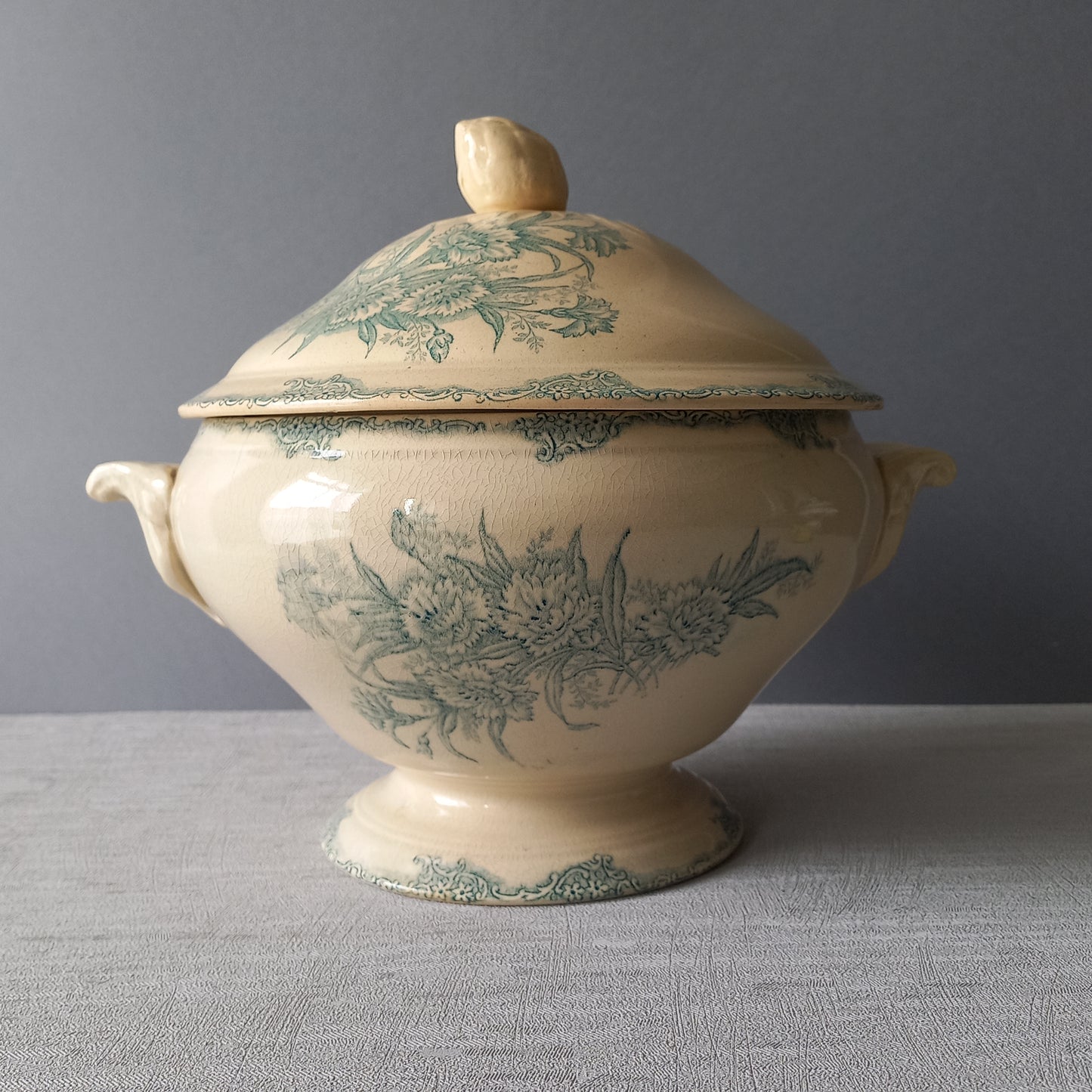 A pretty antique ironstone soup tureen with aged and faded floral transfer pattern in a beautiful shade of blue green or teal. Over time this wonderful old tureen has developed a pleasing faded creamy white finish. In summary, a beautiful piece of authentic antique ironstone from France.