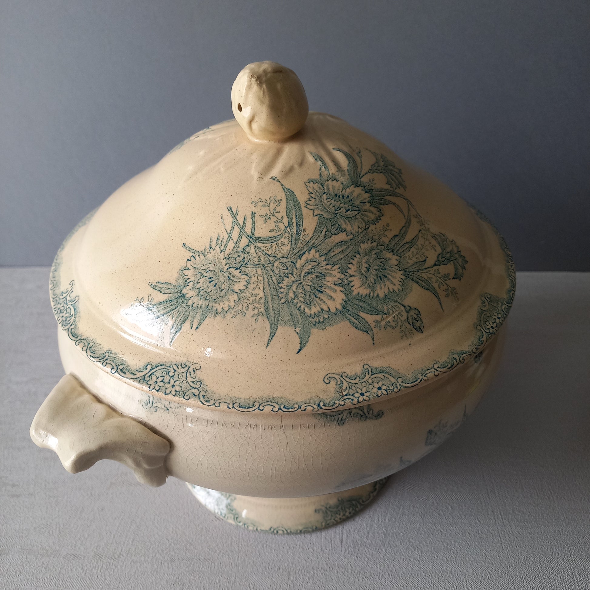 A pretty antique ironstone soup tureen with aged and faded floral transfer pattern in a beautiful shade of blue green or teal. Over time this wonderful old tureen has developed a pleasing faded creamy white finish. In summary, a beautiful piece of authentic antique ironstone from France.