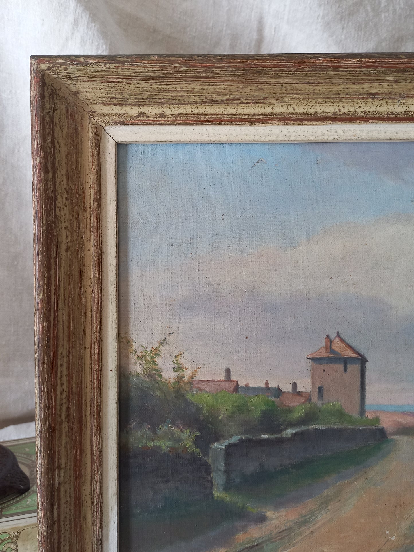 Framed painting of a landscape with a house and trees.