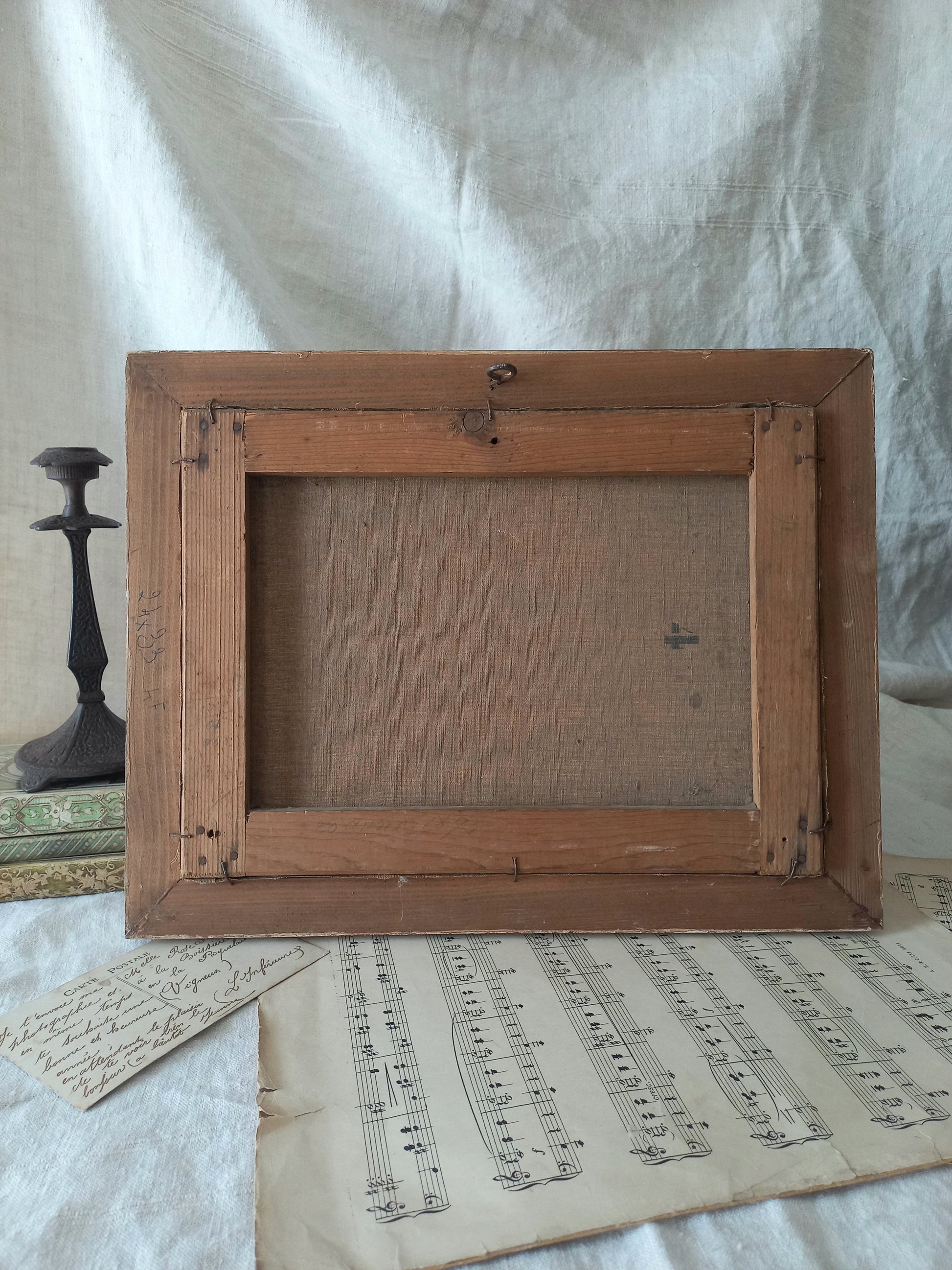 Wooden picture frame on a surface with sheet music and a candlestick