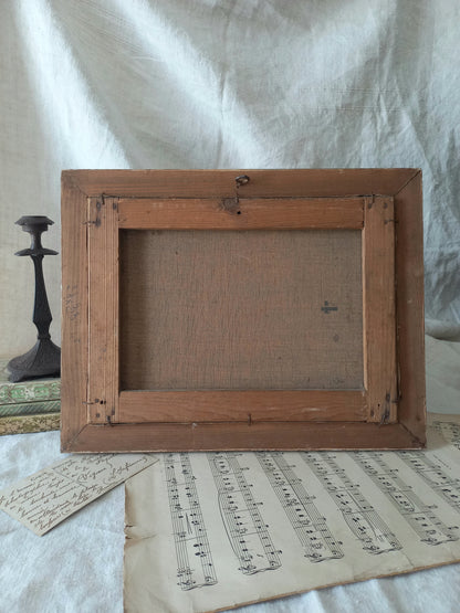 Wooden picture frame on a surface with sheet music and a candlestick