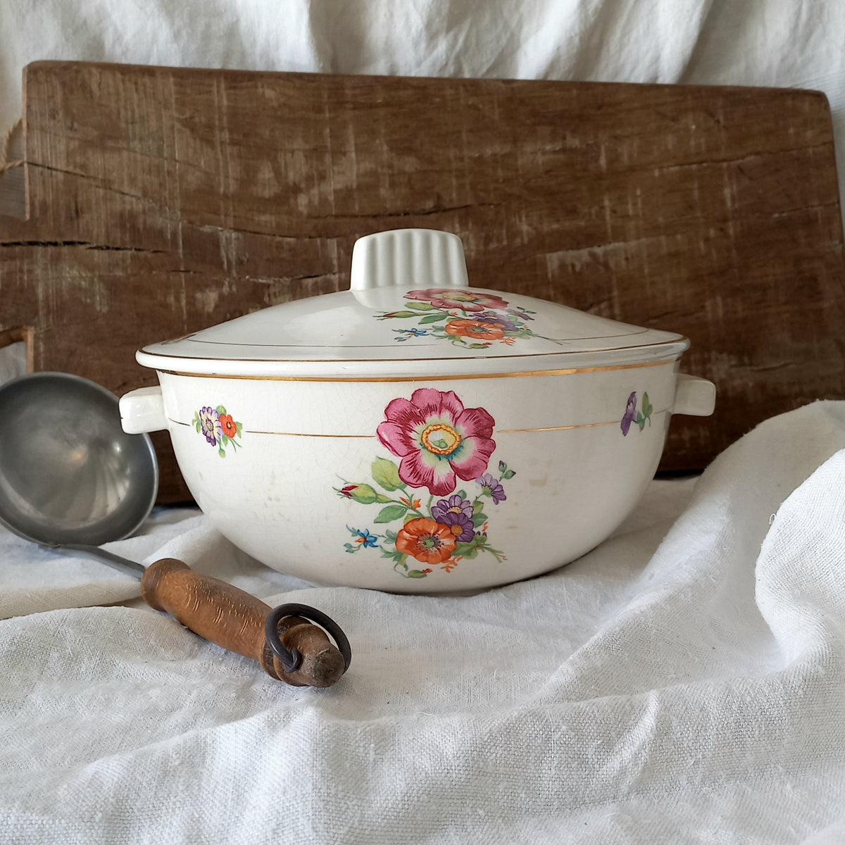 Vintage-style ceramic pot with floral designs on a white fabric background