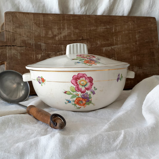 Vintage-style ceramic pot with floral designs on a white fabric background