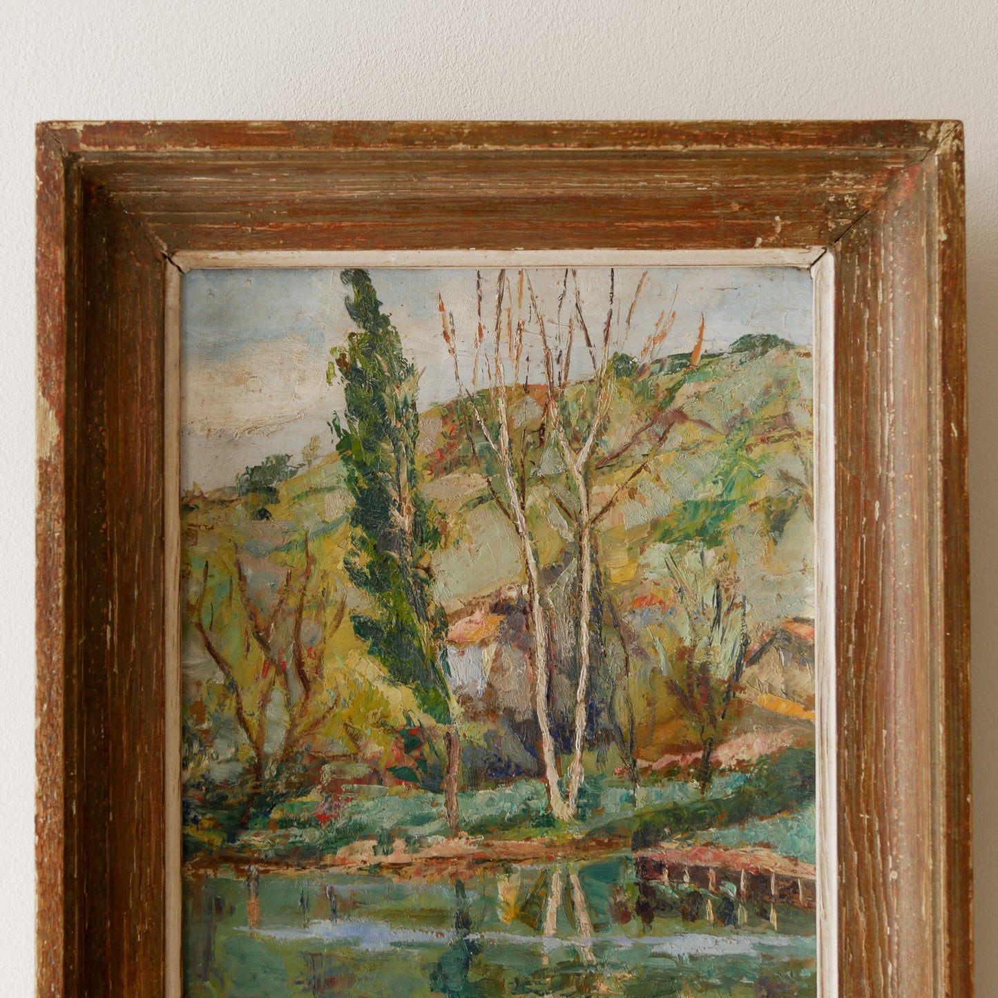 An original vintage landscape oil painting depicting a charming country home in among a wooded area with hills in the background. In the foreground a gentle river reflects the trees in the background.

The painting has been painted by an experienced artist with confident brush strokes - a really wonderful piece of original art.

The painting is presented in an old worn wooden frame which we love and think others will too - it really suits this piece. 