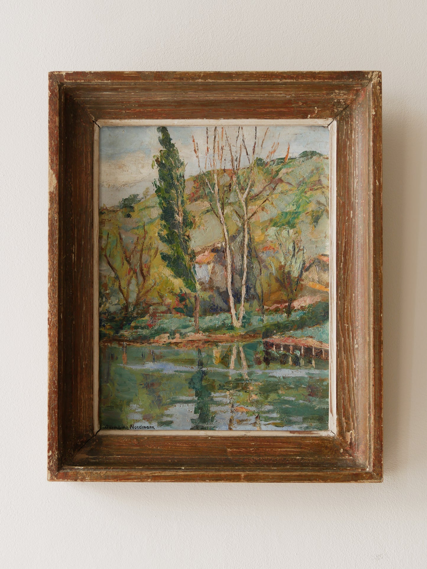 An original vintage landscape oil painting depicting a charming country home in among a wooded area with hills in the background. In the foreground a gentle river reflects the trees in the background.

The painting has been painted by an experienced artist with confident brush strokes - a really wonderful piece of original art.

The painting is presented in an old worn wooden frame which we love and think others will too - it really suits this piece. 