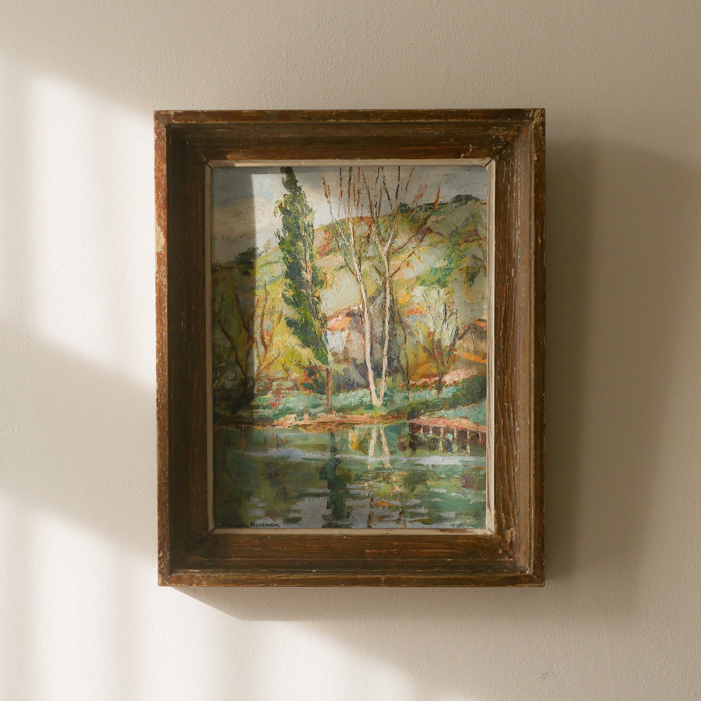 An original vintage landscape oil painting depicting a charming country home in among a wooded area with hills in the background. In the foreground a gentle river reflects the trees in the background.

The painting has been painted by an experienced artist with confident brush strokes - a really wonderful piece of original art.

The painting is presented in an old worn wooden frame which we love and think others will too - it really suits this piece. 