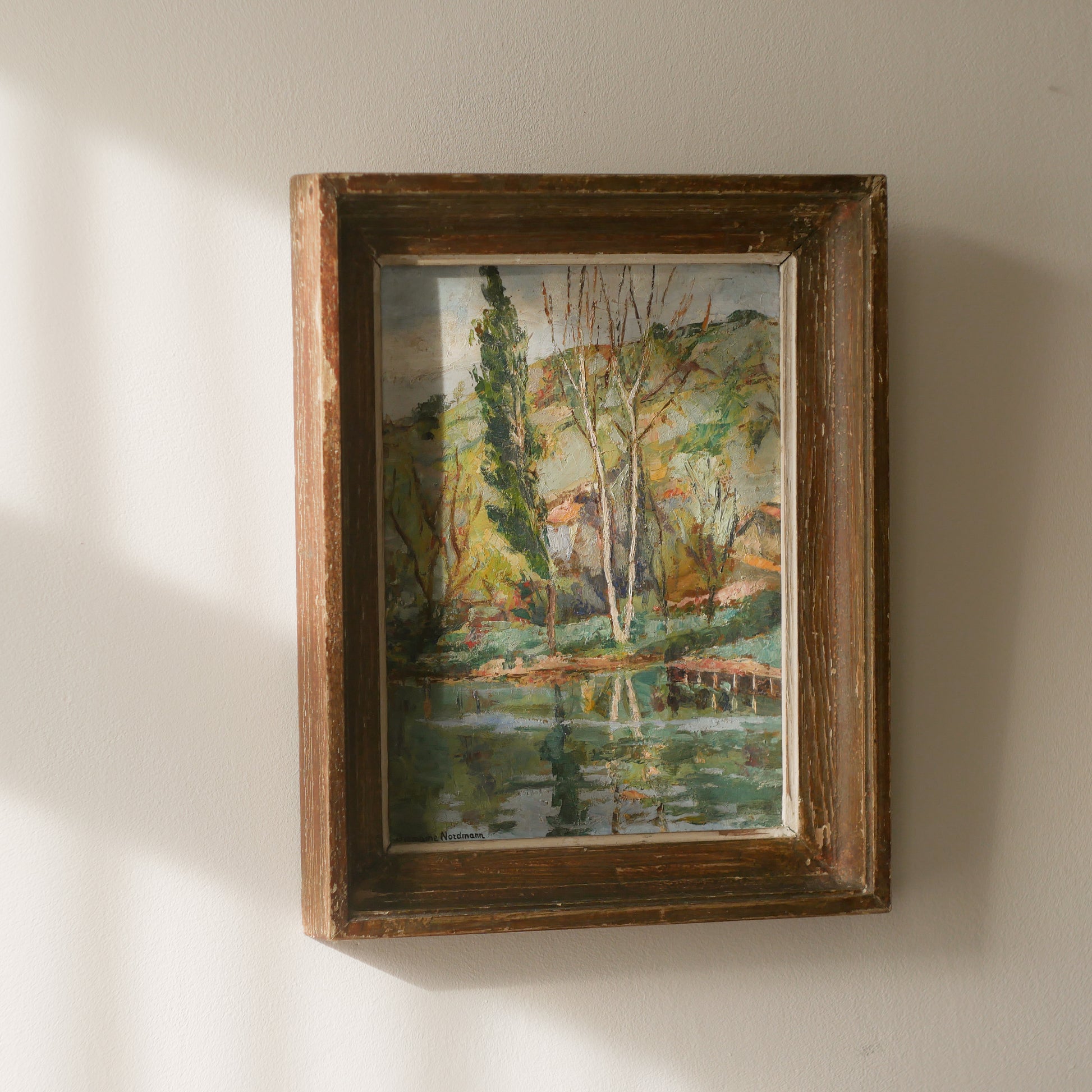 An original vintage landscape oil painting depicting a charming country home in among a wooded area with hills in the background. In the foreground a gentle river reflects the trees in the background.

The painting has been painted by an experienced artist with confident brush strokes - a really wonderful piece of original art.

The painting is presented in an old worn wooden frame which we love and think others will too - it really suits this piece. 