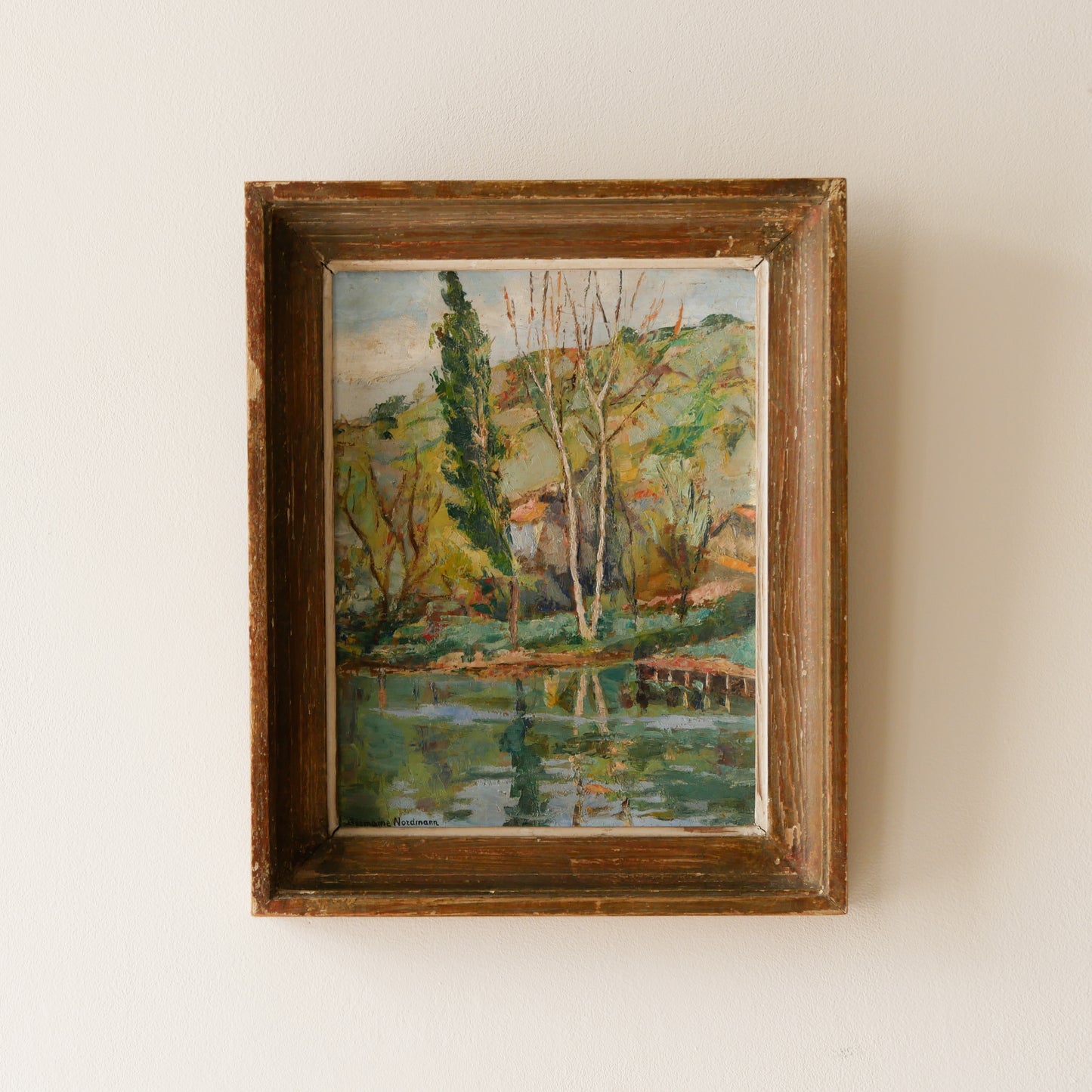 An original vintage landscape oil painting depicting a charming country home in among a wooded area with hills in the background. In the foreground a gentle river reflects the trees in the background.

The painting has been painted by an experienced artist with confident brush strokes - a really wonderful piece of original art.

The painting is presented in an old worn wooden frame which we love and think others will too - it really suits this piece. 