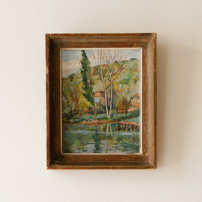 An original vintage landscape oil painting depicting a charming country home in among a wooded area with hills in the background. In the foreground a gentle river reflects the trees in the background.

The painting has been painted by an experienced artist with confident brush strokes - a really wonderful piece of original art.

The painting is presented in an old worn wooden frame which we love and think others will too - it really suits this piece. 