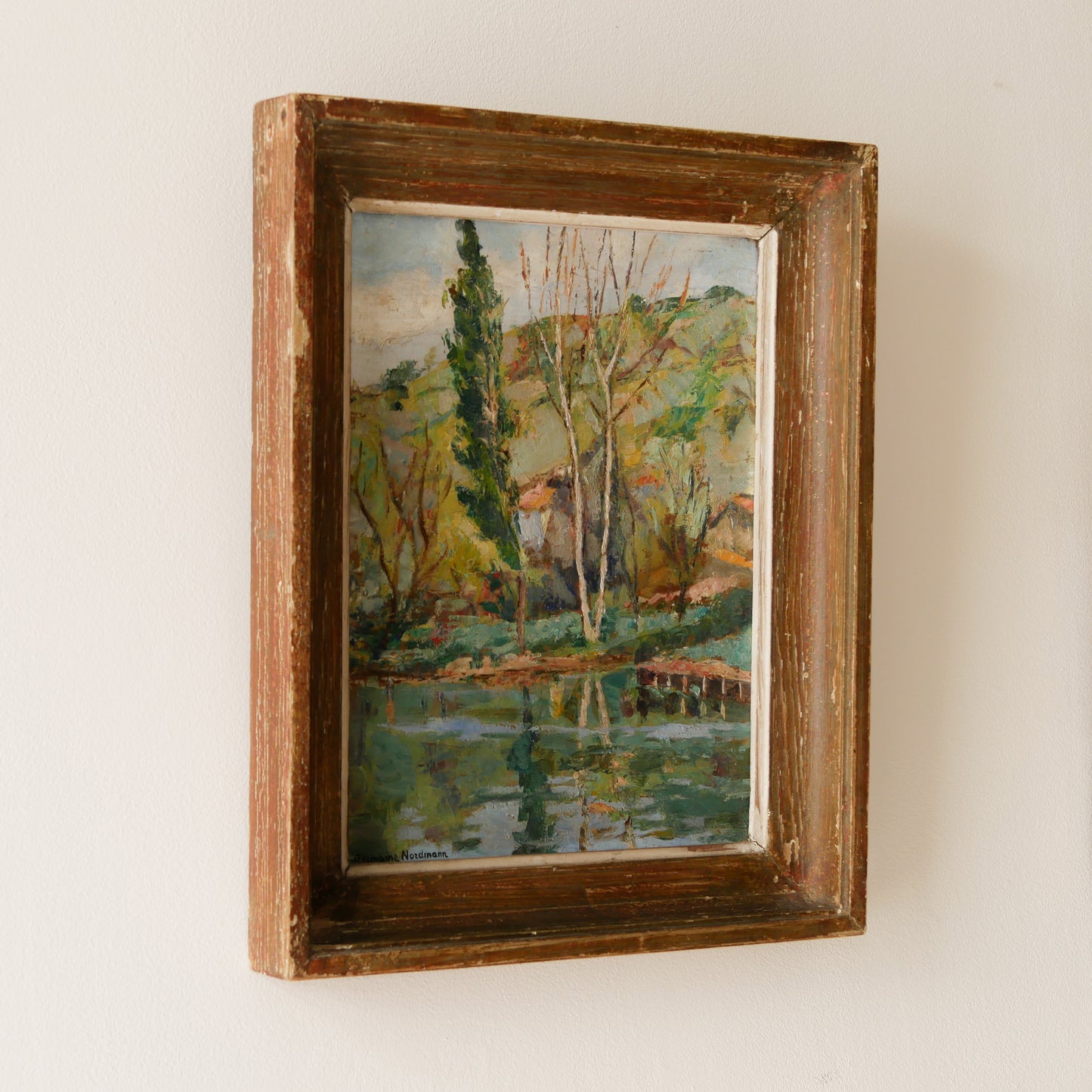 An original vintage landscape oil painting depicting a charming country home in among a wooded area with hills in the background. In the foreground a gentle river reflects the trees in the background.

The painting has been painted by an experienced artist with confident brush strokes - a really wonderful piece of original art.

The painting is presented in an old worn wooden frame which we love and think others will too - it really suits this piece. 