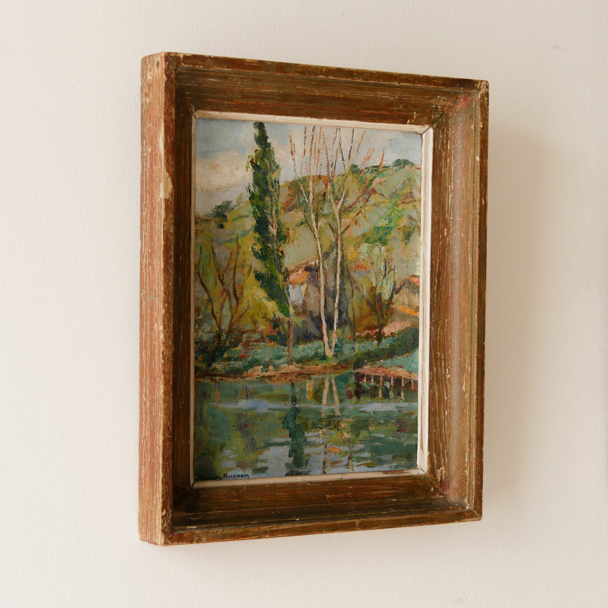 An original vintage landscape oil painting depicting a charming country home in among a wooded area with hills in the background. In the foreground a gentle river reflects the trees in the background.

The painting has been painted by an experienced artist with confident brush strokes - a really wonderful piece of original art.

The painting is presented in an old worn wooden frame which we love and think others will too - it really suits this piece. 
