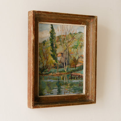 An original vintage landscape oil painting depicting a charming country home in among a wooded area with hills in the background. In the foreground a gentle river reflects the trees in the background.

The painting has been painted by an experienced artist with confident brush strokes - a really wonderful piece of original art.

The painting is presented in an old worn wooden frame which we love and think others will too - it really suits this piece. 