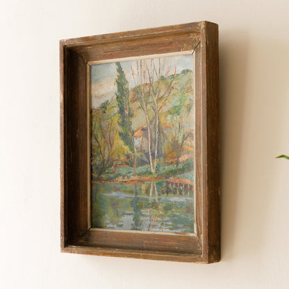An original vintage landscape oil painting depicting a charming country home in among a wooded area with hills in the background. In the foreground a gentle river reflects the trees in the background.

The painting has been painted by an experienced artist with confident brush strokes - a really wonderful piece of original art.

The painting is presented in an old worn wooden frame which we love and think others will too - it really suits this piece. 