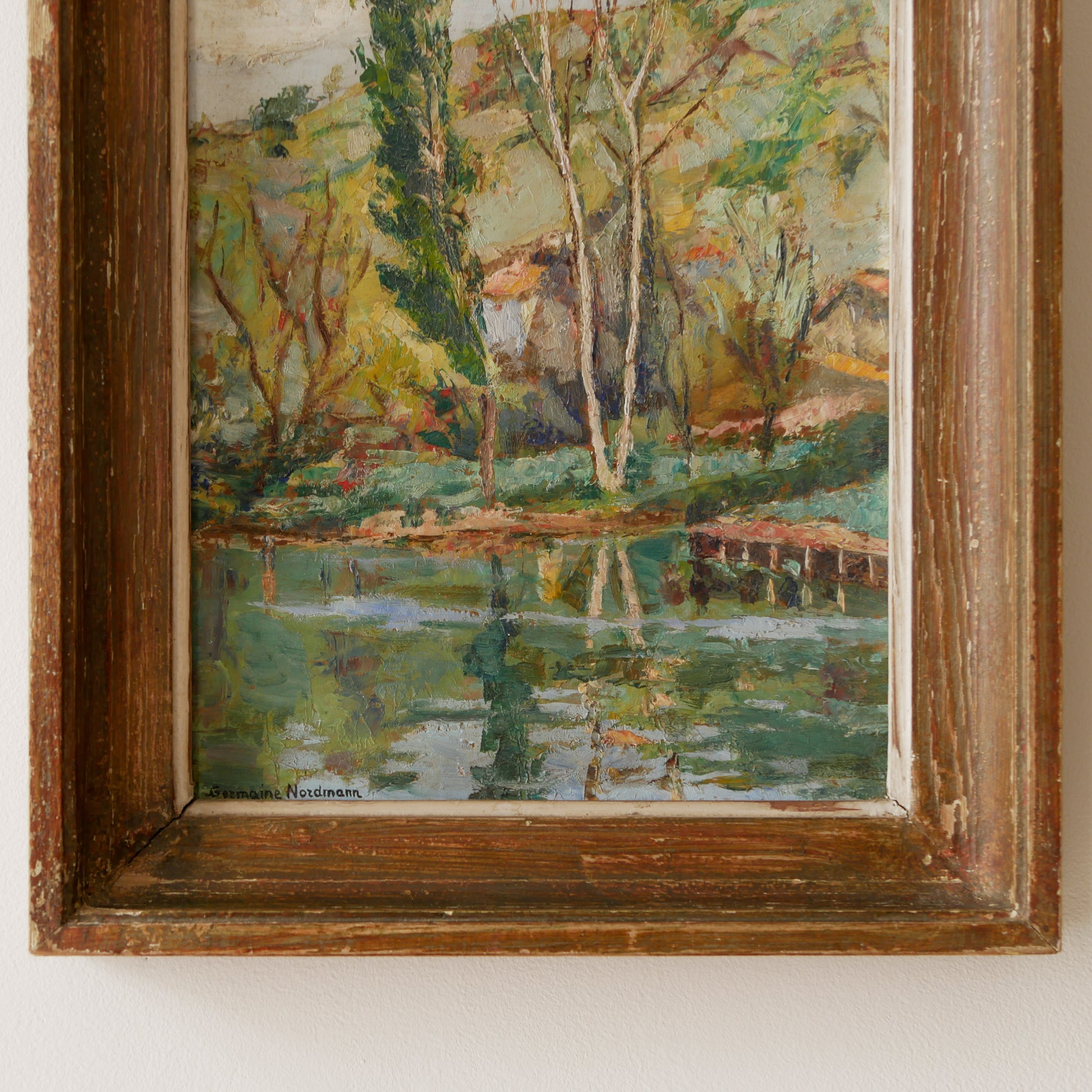 An original vintage landscape oil painting depicting a charming country home in among a wooded area with hills in the background. In the foreground a gentle river reflects the trees in the background.

The painting has been painted by an experienced artist with confident brush strokes - a really wonderful piece of original art.

The painting is presented in an old worn wooden frame which we love and think others will too - it really suits this piece. 