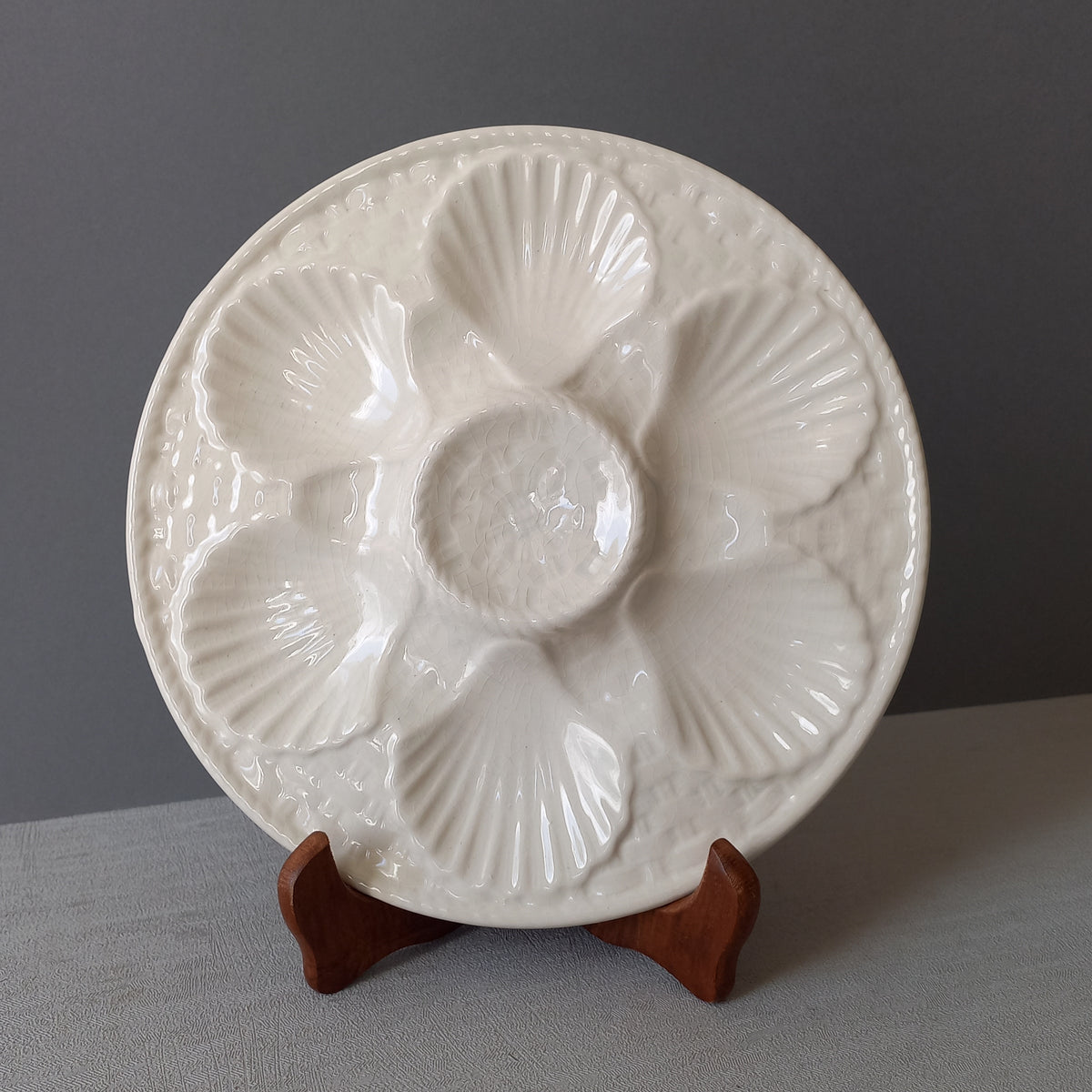A beautiful French vintage oyster plate by Chantilly in a lovely shade of creamy white. This plate is a heavy, quality piece with six scalloped hollows for your oysters and a central hollow for a piece of lemon. There is a basket weave pattern and also a twisted rope pattern with some wonderful crazing in the glaze of this superb majolica plate which make it an eye catching piece of decor.