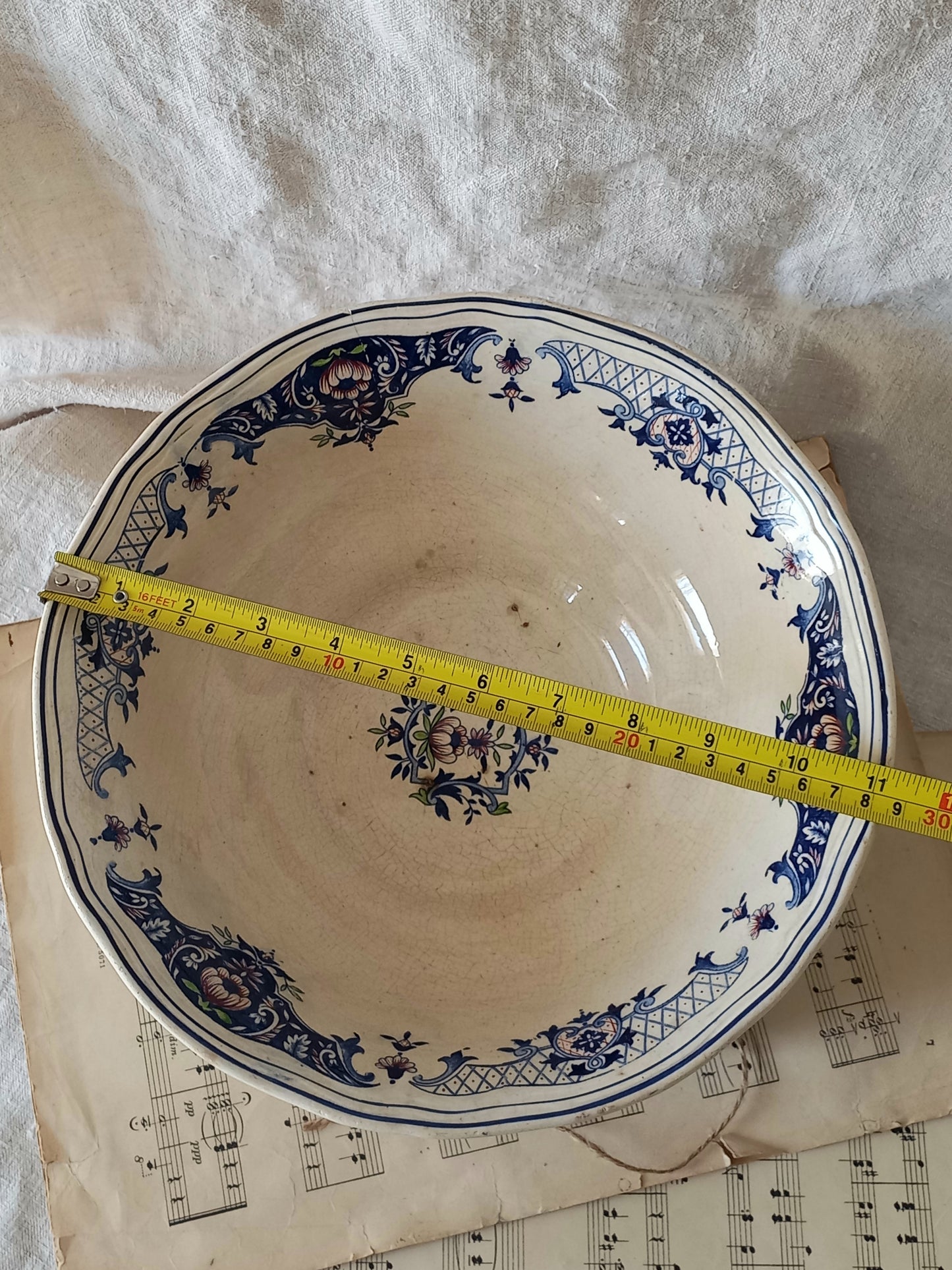 Large French antique decorative footed bowl with a stunning floral pattern in a decorative setting  with a tape measure for reference.