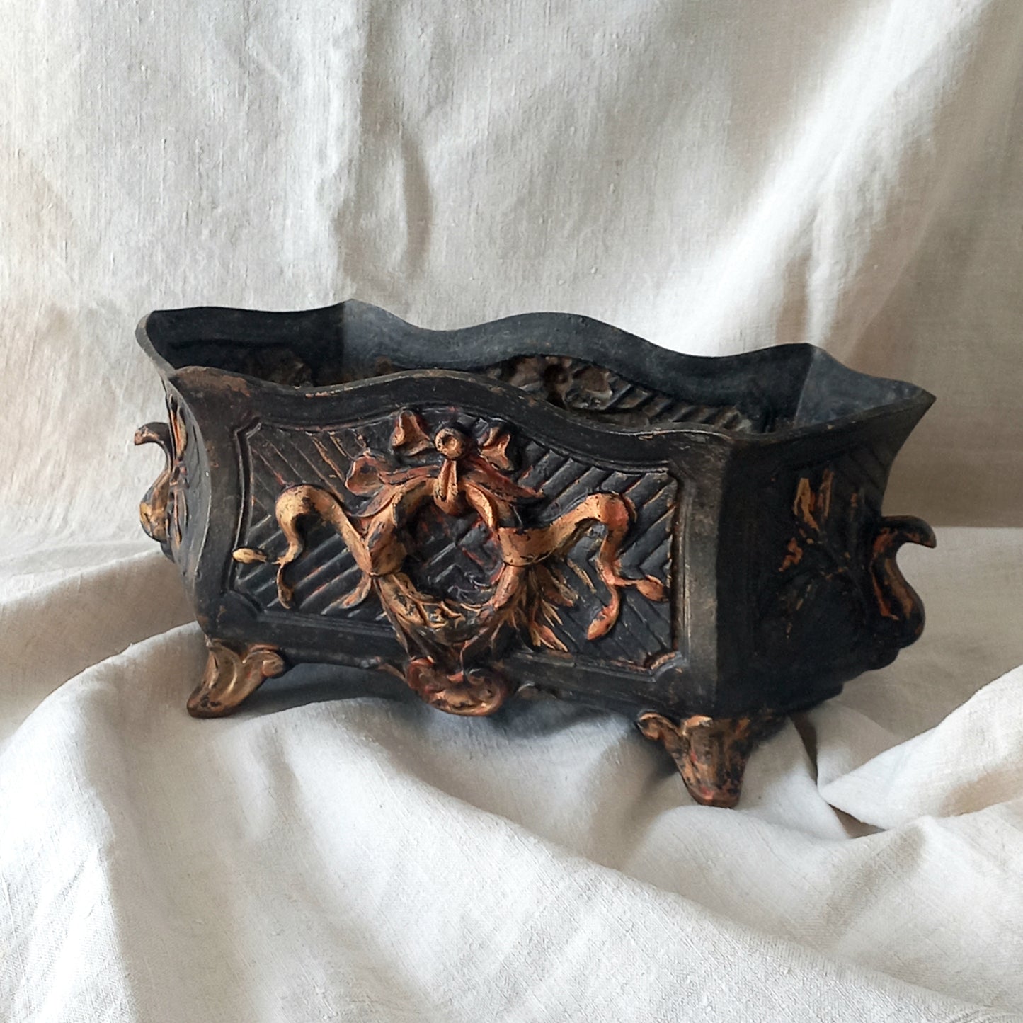 A stunning French antique decorative cast iron planter with patina of age suitable for both interior and exterior use - we rarely come across them these days so this was an exciting find.

The planter is in a striking and wonderfully aged black colour with gold coloured detailing in relief - there's some great paint chipping off areas of the gold paint showing small areas of red beneath, and also chipping from the black paint showing rusty patina, all of which add to the antique character of this beautiful 