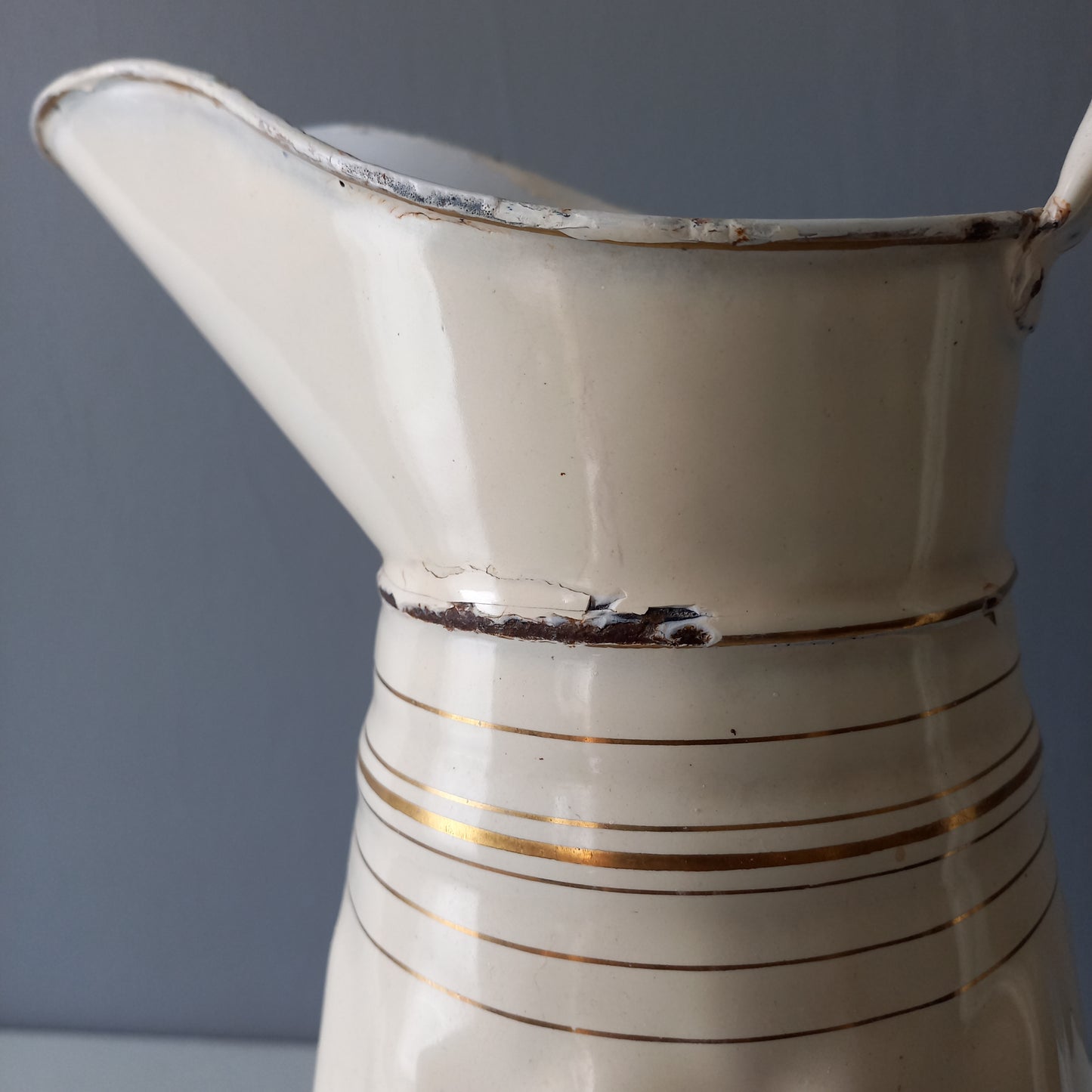 Large antique enamel metal pitcher in cream color with gold trim from France